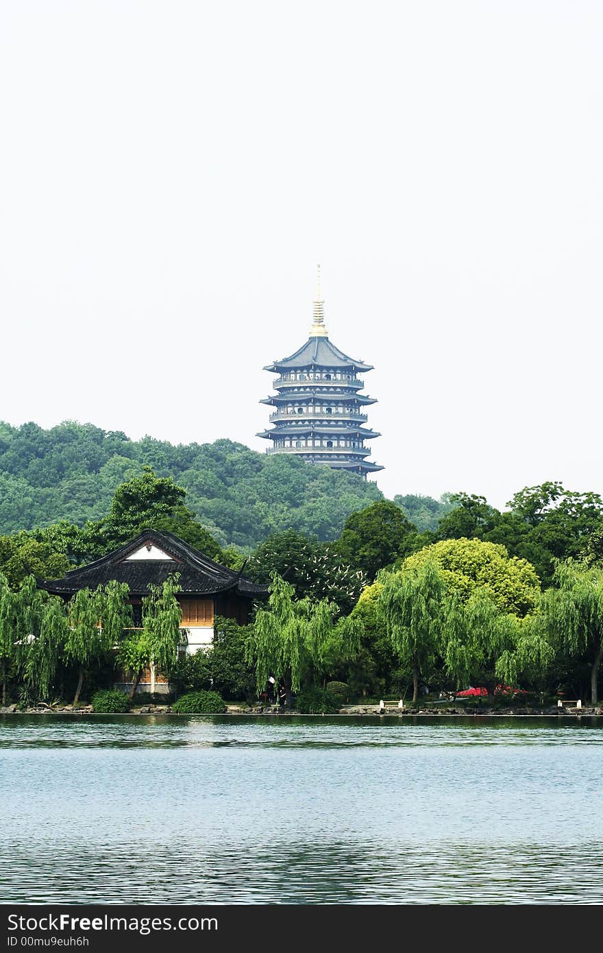 Asian tower near a lake with Asian house and green willow trees. Asian tower near a lake with Asian house and green willow trees.