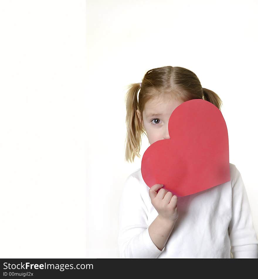 Little girl dressed in white holding a valentine heart. Little girl dressed in white holding a valentine heart