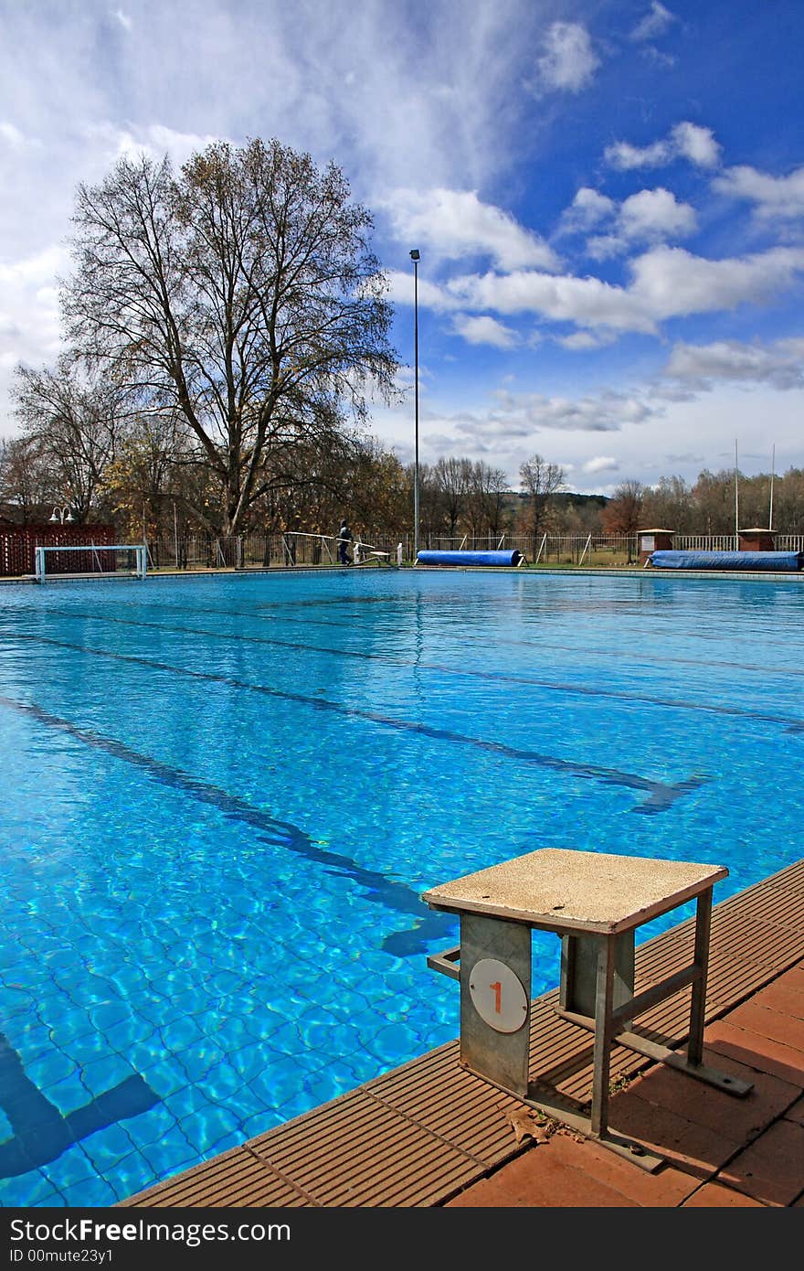 Bright blue image of school pool with starting block on a cloudy day. Bright blue image of school pool with starting block on a cloudy day.