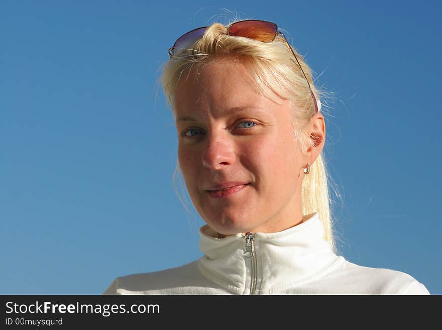 Portrait of a young attractive girl  on the blue sky background. Portrait of a young attractive girl  on the blue sky background