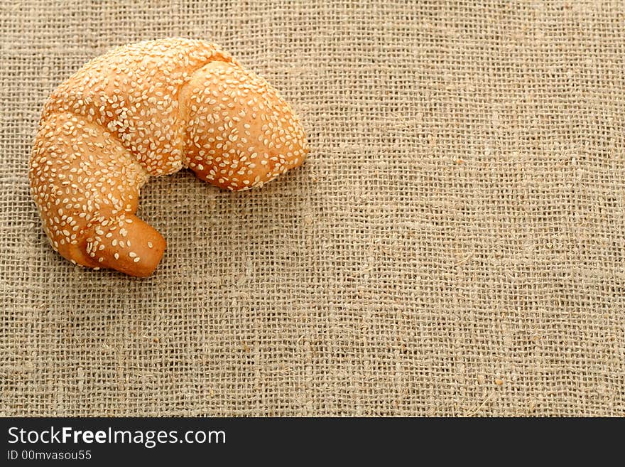 Croissant with sesame on a sacking background. Croissant with sesame on a sacking background