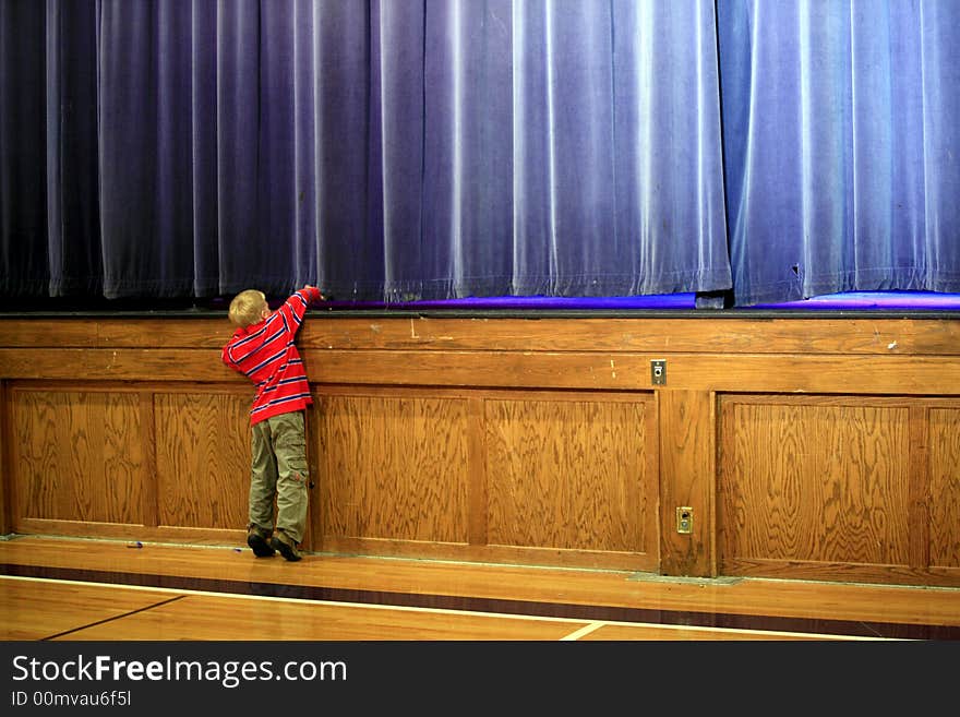 Small child peeking under the Stage curtian just before the production begins. Small child peeking under the Stage curtian just before the production begins