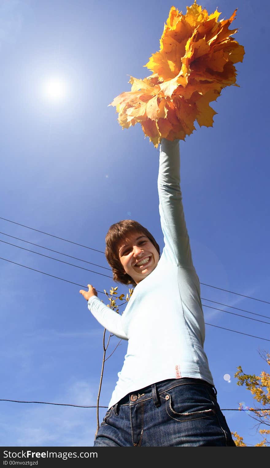 A girl in a chaplet from yellow maple leaves puts a person a sun