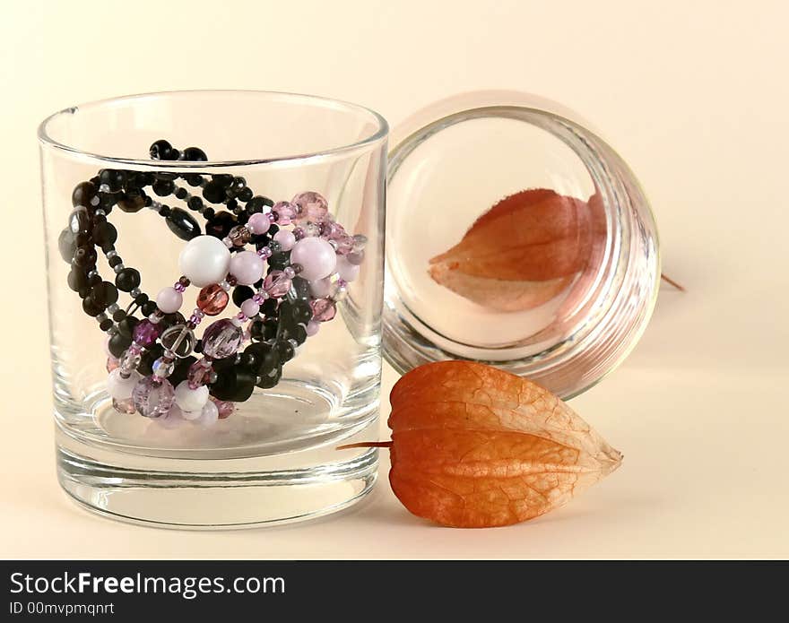 Still life with dry flowers, dry ground cherry (b.n. cape gooseberry), two bracelets and two glasses on sandy yellow background. Still life with dry flowers, dry ground cherry (b.n. cape gooseberry), two bracelets and two glasses on sandy yellow background