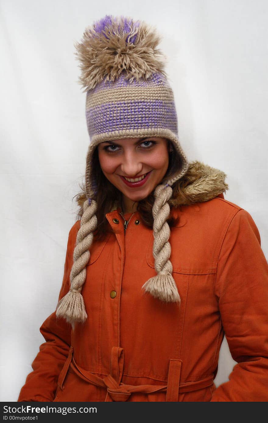 Winter portrait of beautiful young woman which freezes in an orange jacket