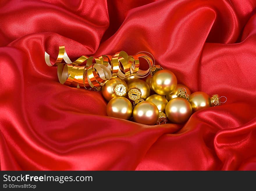 Gold christmas balls on the red satin background. Gold christmas balls on the red satin background