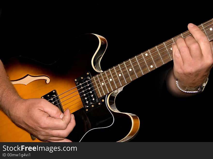 Hands planing a guitar on a black background. Hands planing a guitar on a black background