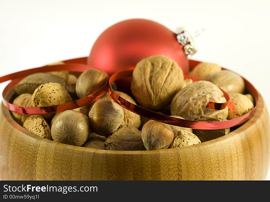 Wooden bowl with variety of nuts with red ornamental ball. Wooden bowl with variety of nuts with red ornamental ball