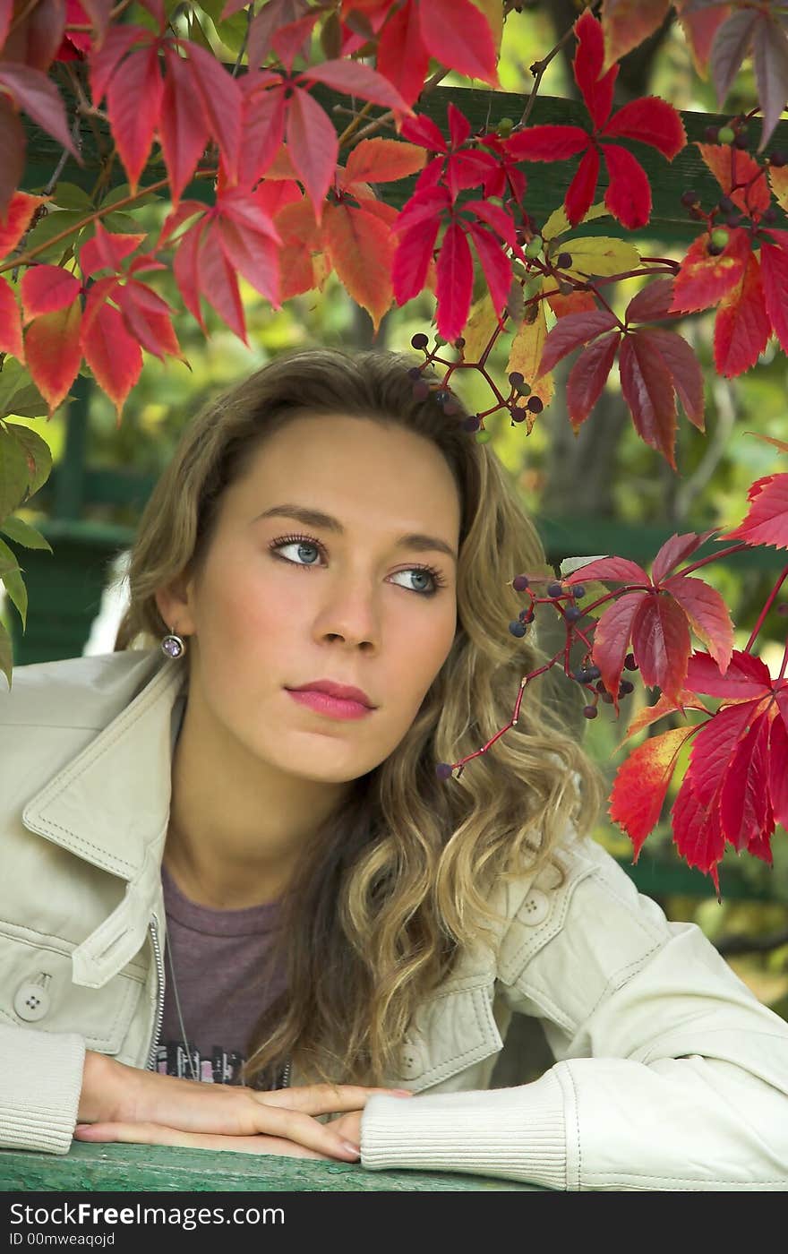 The beautiful blonde in red leaves of grapes