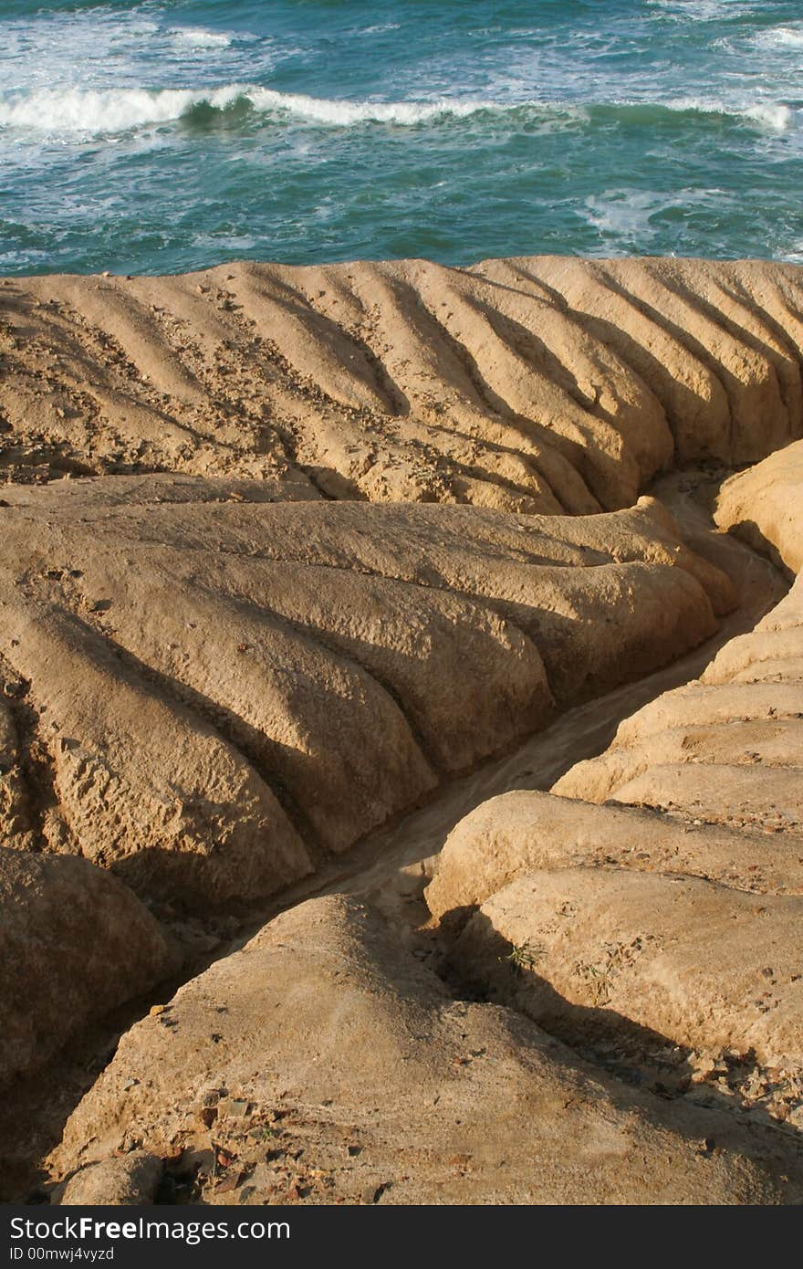 Deep eroded gullies transitioning abruptly to a stormy sea. Deep eroded gullies transitioning abruptly to a stormy sea.