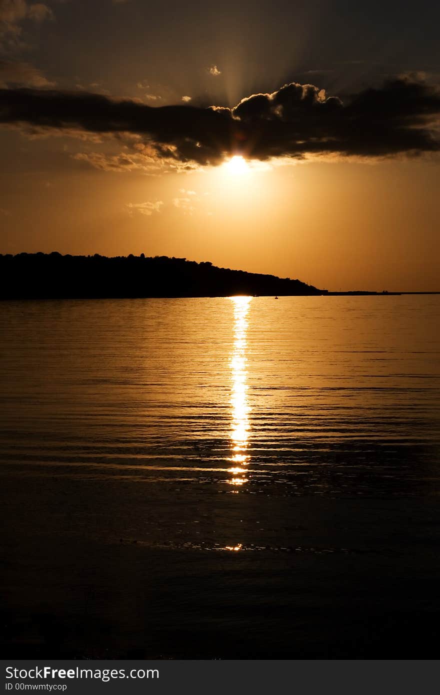 Sun behind a cloud and reflection on sea