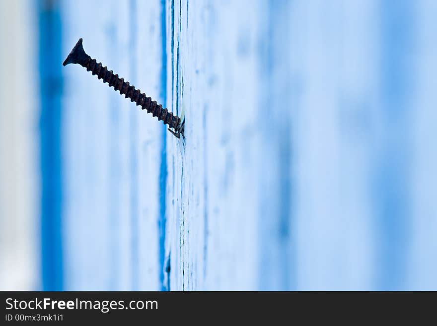 Old screw on a blue painted wall