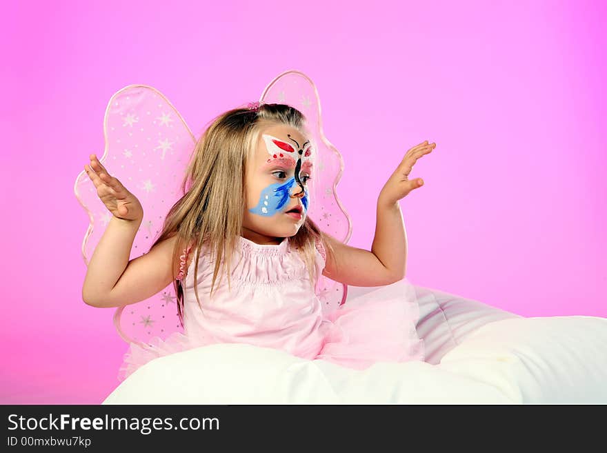 A studio shot of little girl dressed as butterfly on pink background. A studio shot of little girl dressed as butterfly on pink background