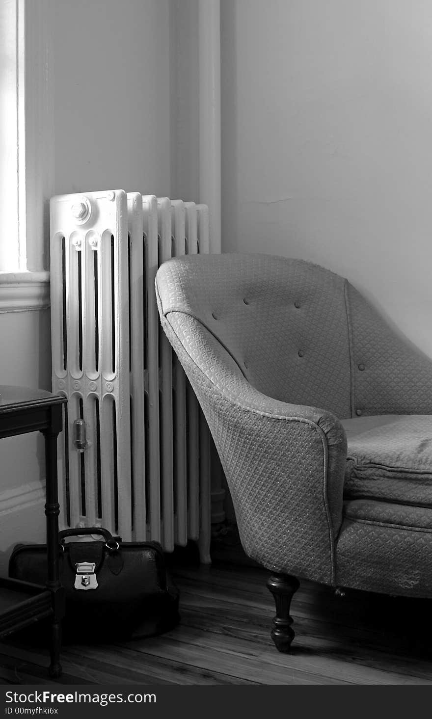 Old living room showing steam radiator, chaise lounge sofa, end table and black leather doctor bag. Old living room showing steam radiator, chaise lounge sofa, end table and black leather doctor bag