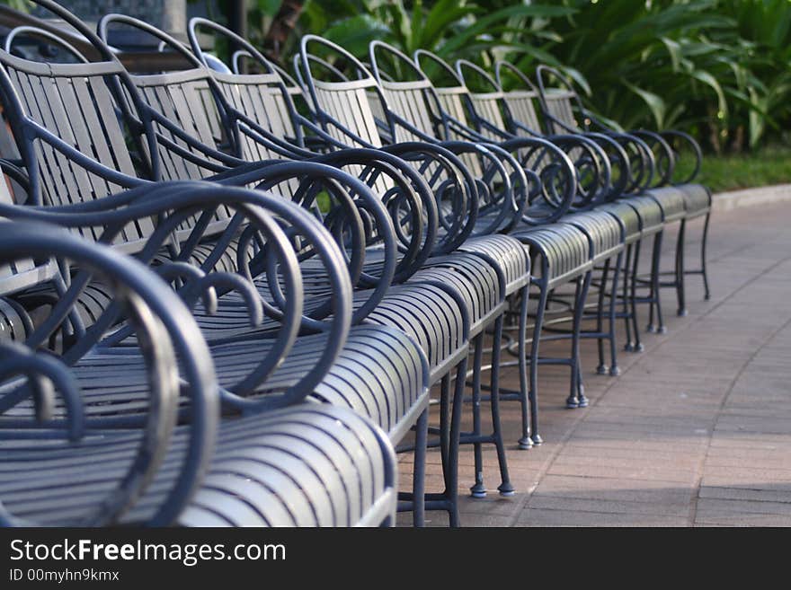 A row of chairs in a park like setting.