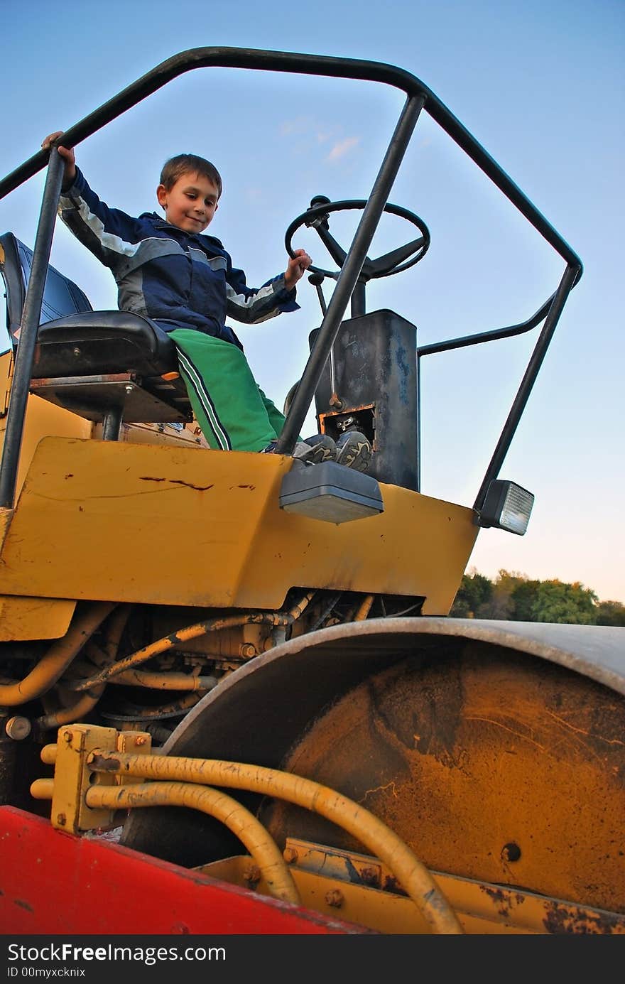 Cute happy boy driving steamroller