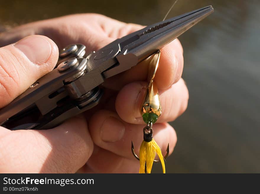 Man holding a lure and getting it attached to the line. Man holding a lure and getting it attached to the line.