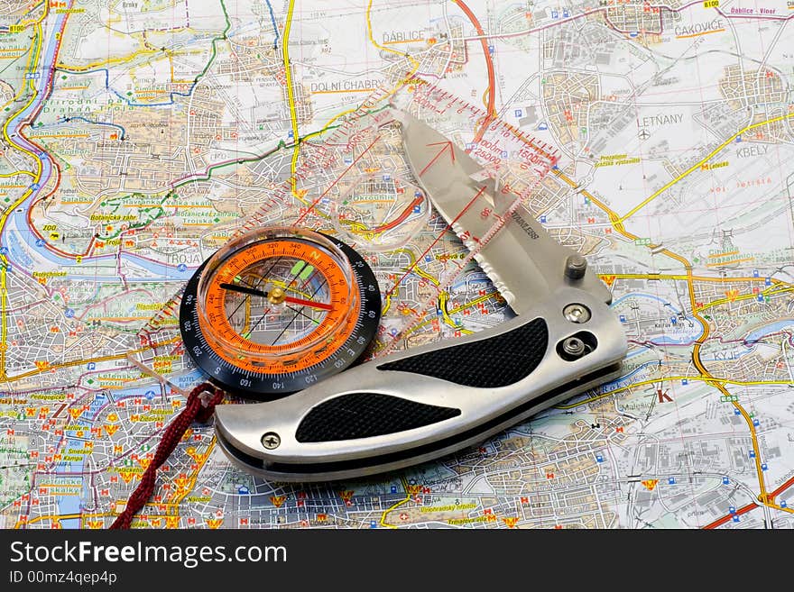 A compass and a knife lying on a map - close up. A compass and a knife lying on a map - close up