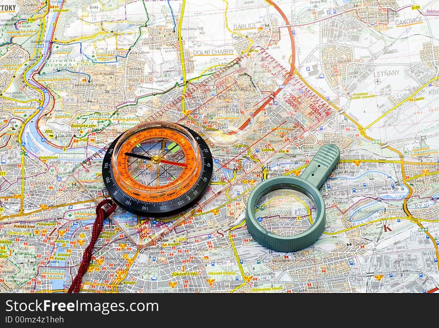 A compass and a handglass lying on a map - close up. A compass and a handglass lying on a map - close up