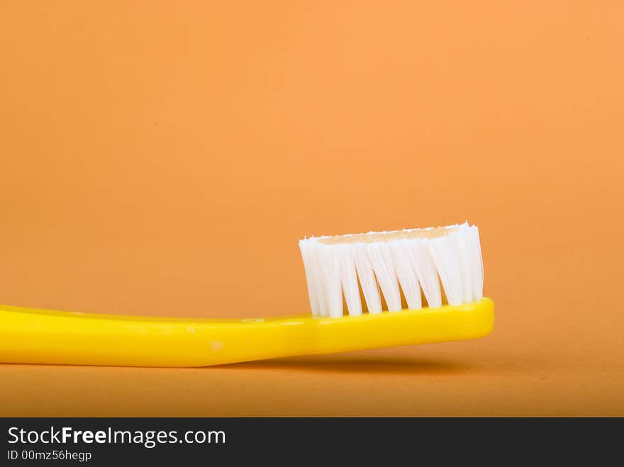 Yellow toothbrush on an orange background.