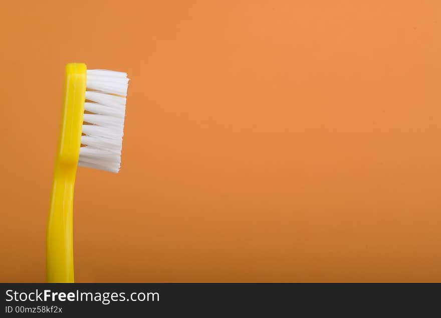 Yellow toothbrush on an orange background.