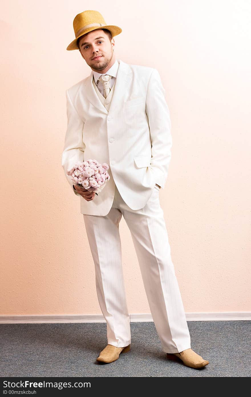 Young groom in wedding wear with bouquet of chrysanthemum. Special pink toned photo f/x. Young groom in wedding wear with bouquet of chrysanthemum. Special pink toned photo f/x