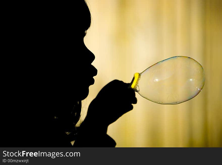 Silhouette of a little girl making a big bubble against yellow background. Silhouette of a little girl making a big bubble against yellow background.