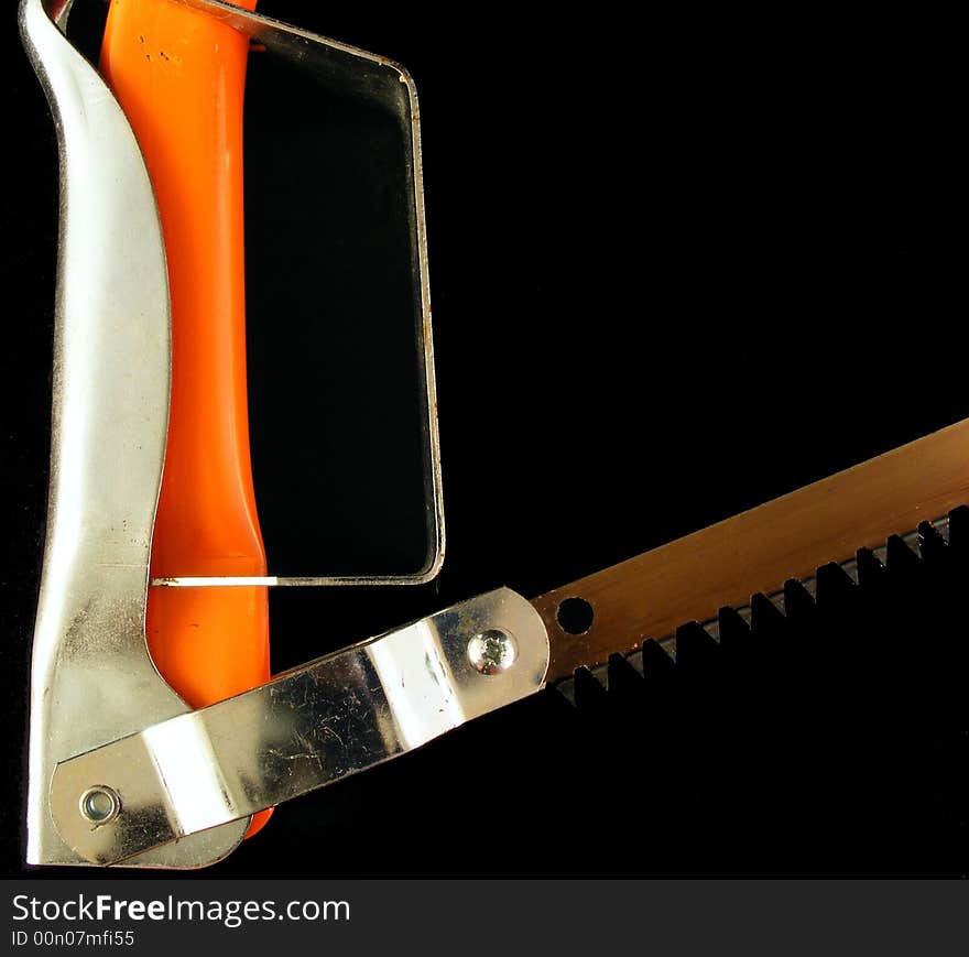 An orange hacksaw against a black background. An orange hacksaw against a black background.