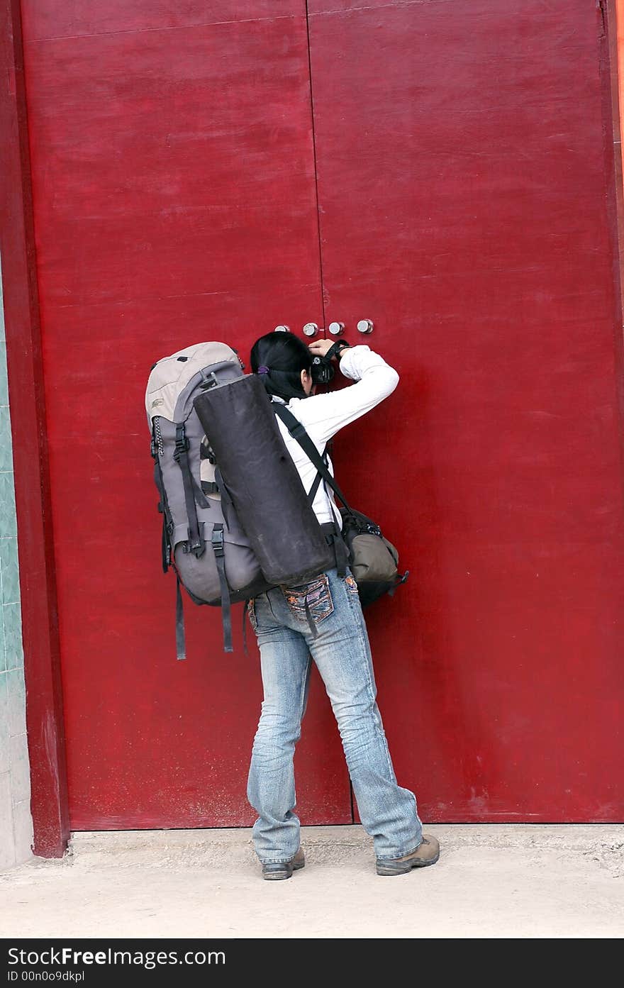 A hiker viewed  frow the clack between the red door.