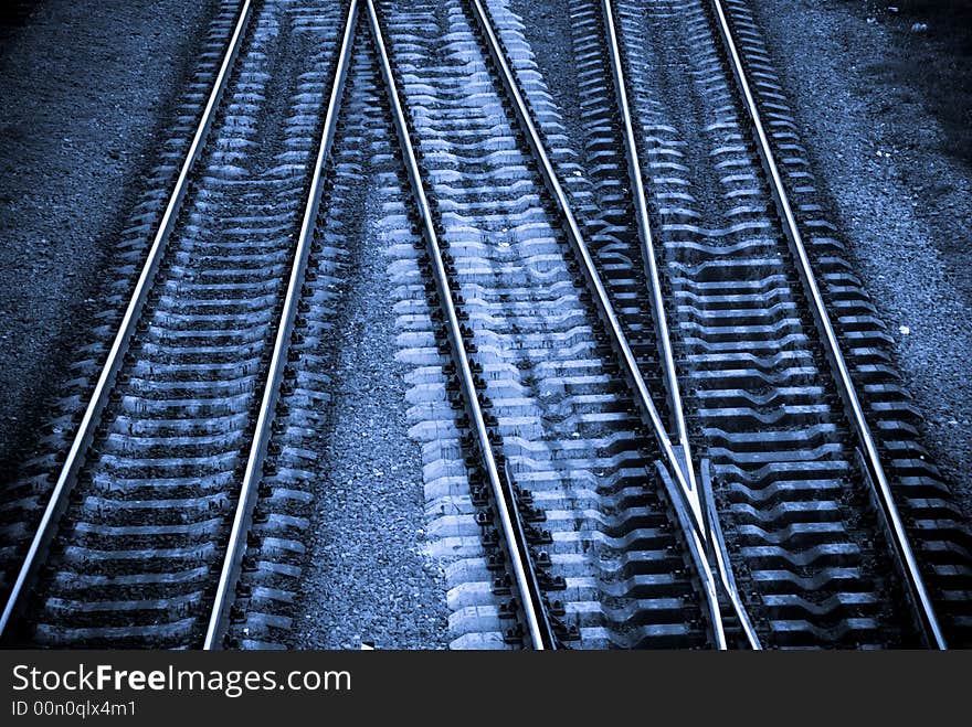 Three crossing railway tracks in cold blue tones