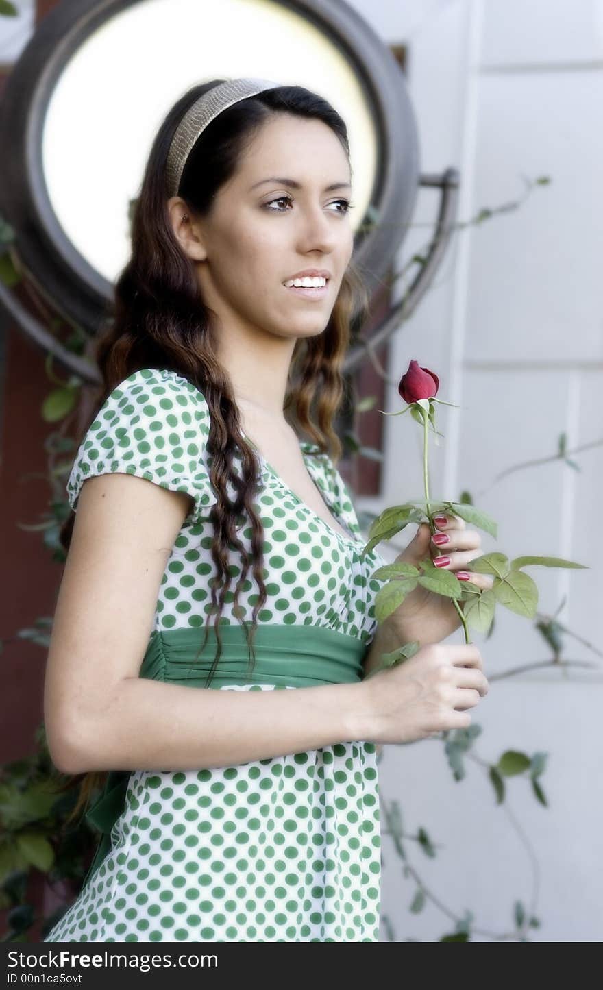 Attractive young woman in green dress holding a single  red rose. Attractive young woman in green dress holding a single  red rose