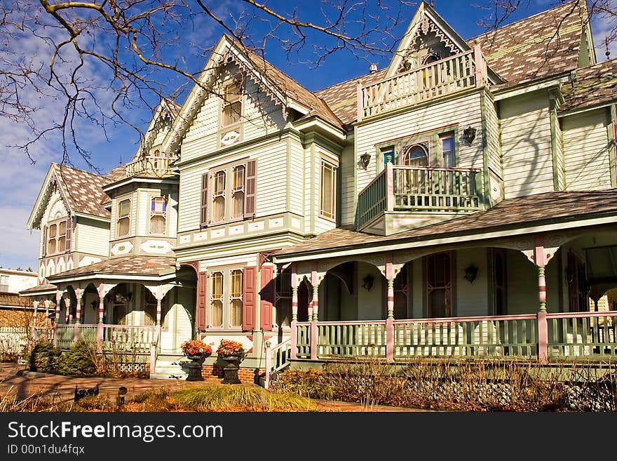 An outside view of a large Victorian mansion with elaborate woodwork on the many gables porches and windows.