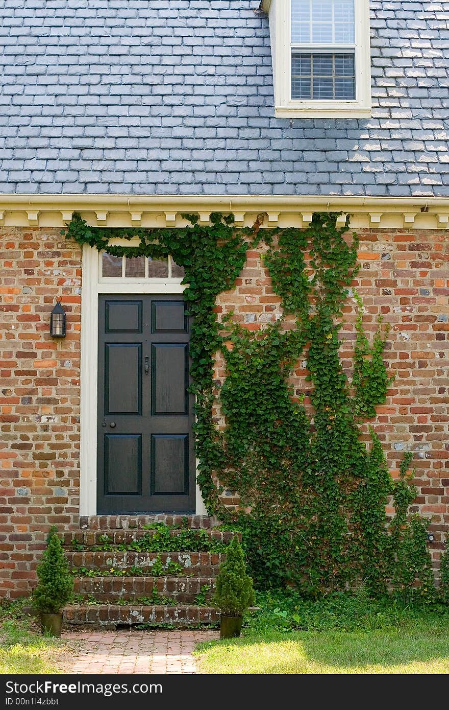 Entrance of brick colonial house with creeping moss covering it. Entrance of brick colonial house with creeping moss covering it