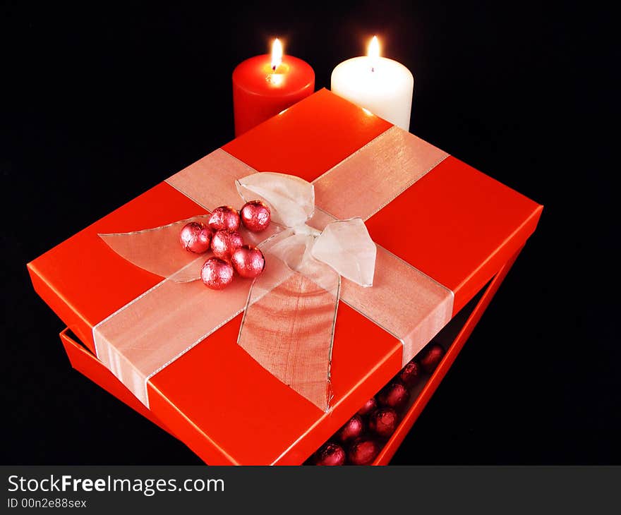 A gift package and candles against a black background. A gift package and candles against a black background.