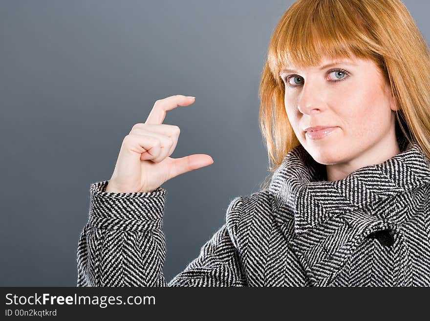 Woman with coat showing a small gap or small thing with her fingers. Woman with coat showing a small gap or small thing with her fingers.