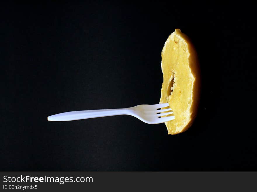 Plastic fork sticking in toasted bagel with butter. Plastic fork sticking in toasted bagel with butter