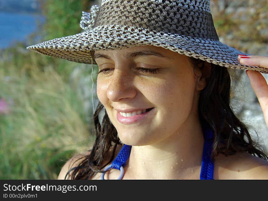 A girl wearing a hat against the hot summer sun at the beach in montenegro. A girl wearing a hat against the hot summer sun at the beach in montenegro