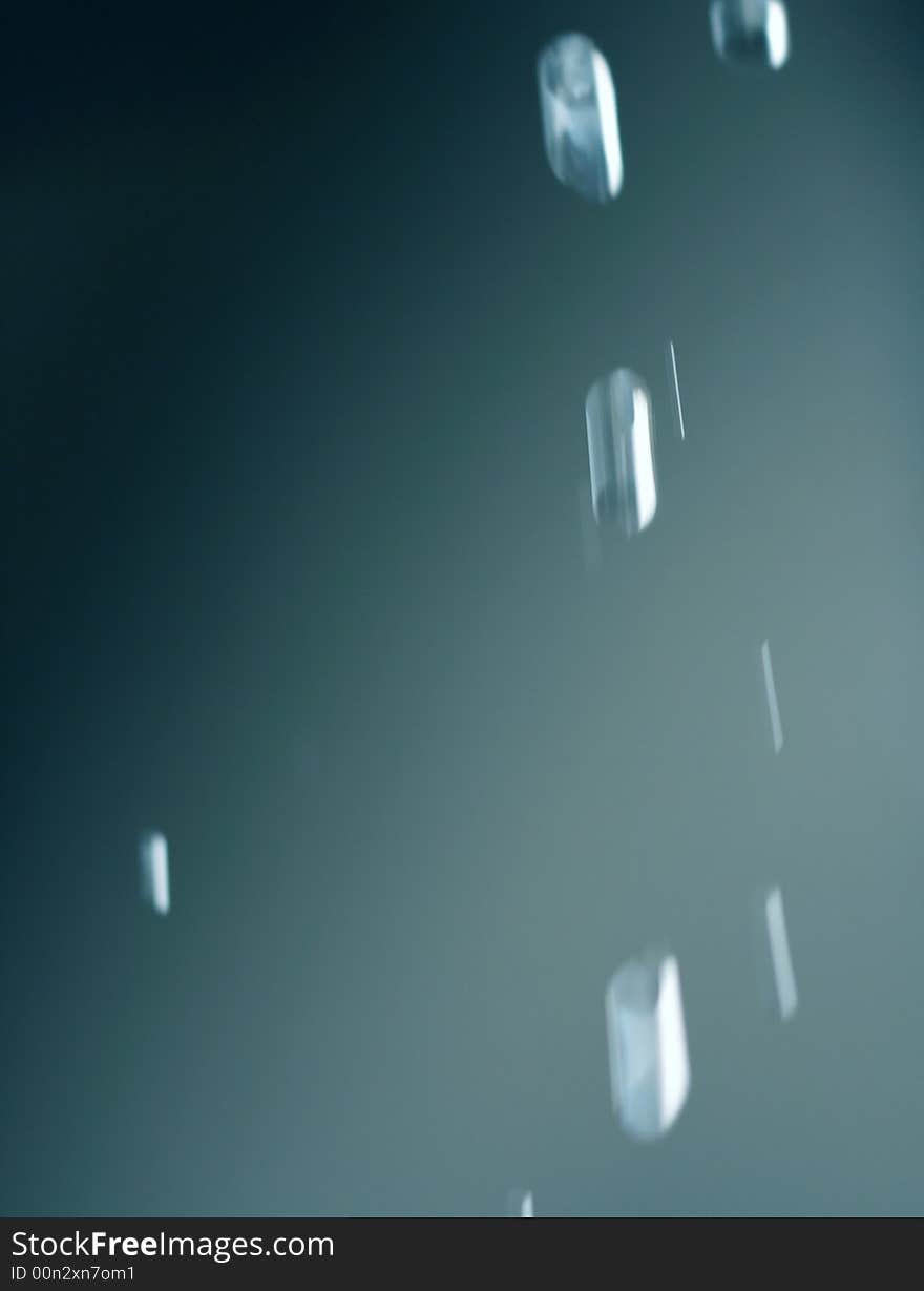 Falling water drops from eaves - abstract blue background