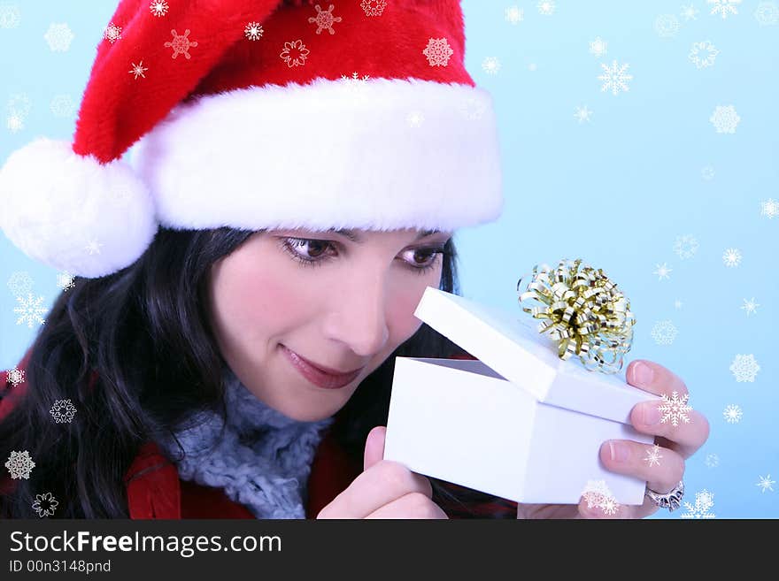 A young woman opening a Christmas gift, snowflakes surround her