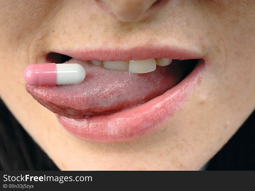 Young woman's face with pink pill. Young woman's face with pink pill