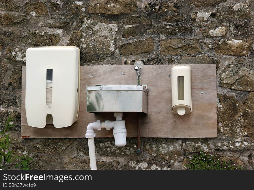 Outdoor metal wash basin, plastic hand towel and soap dispenser fixed to an old stone wall. Outdoor metal wash basin, plastic hand towel and soap dispenser fixed to an old stone wall.