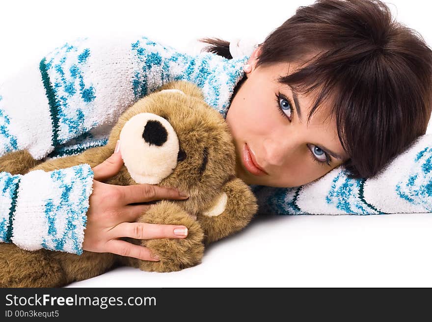 Lying charming brunette embraces teddy bear isolated on white. Lying charming brunette embraces teddy bear isolated on white