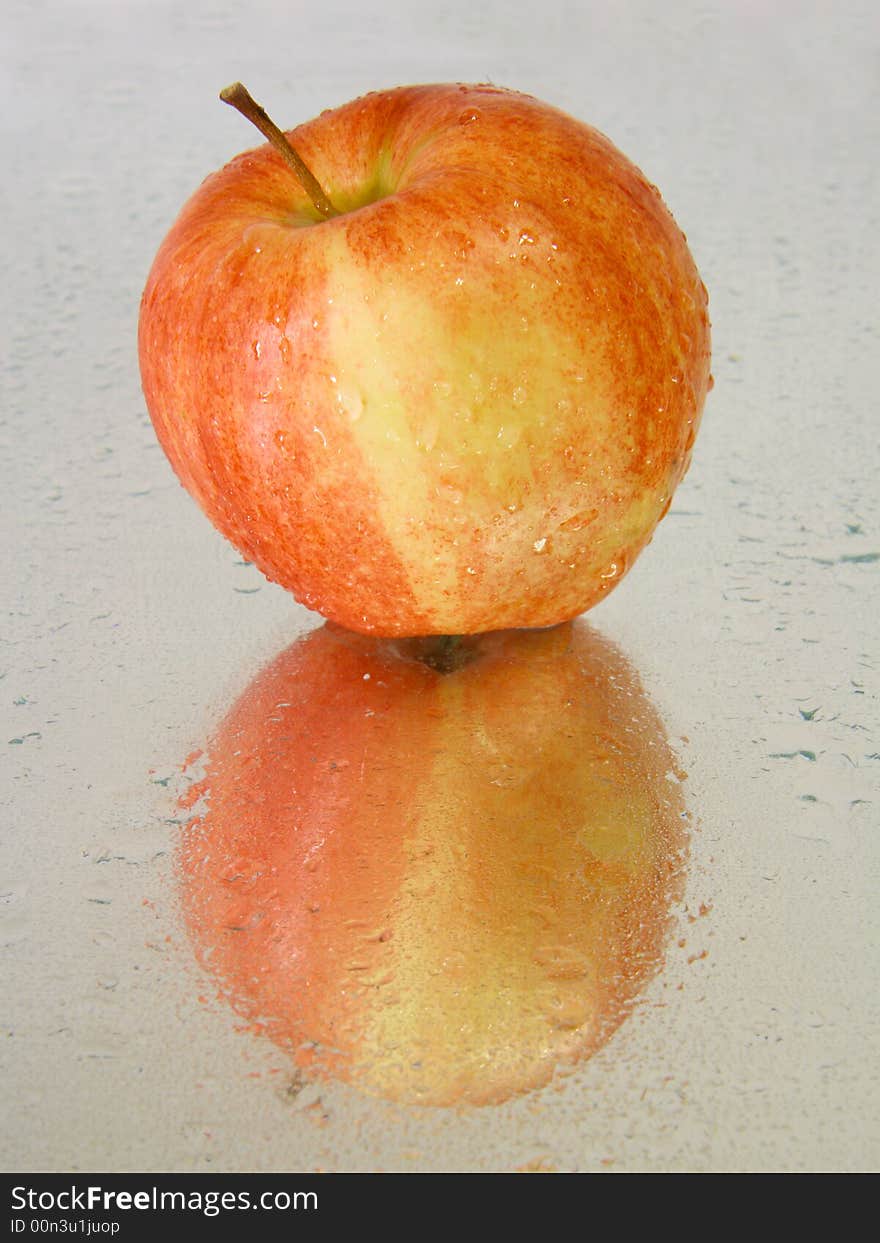 Red wet apple with reflections on a wet surface