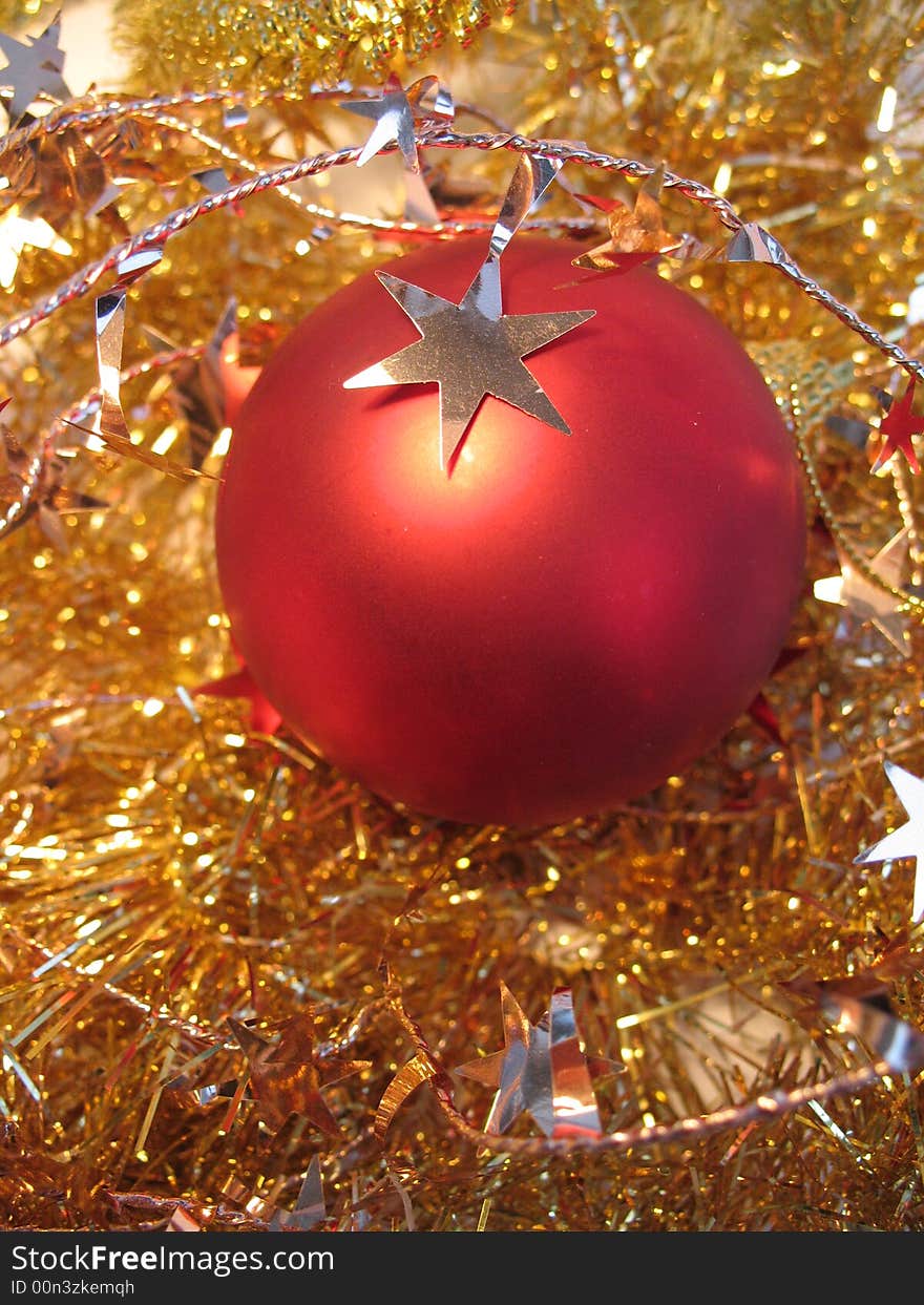 Red christmas ball with golden star on golden glare background