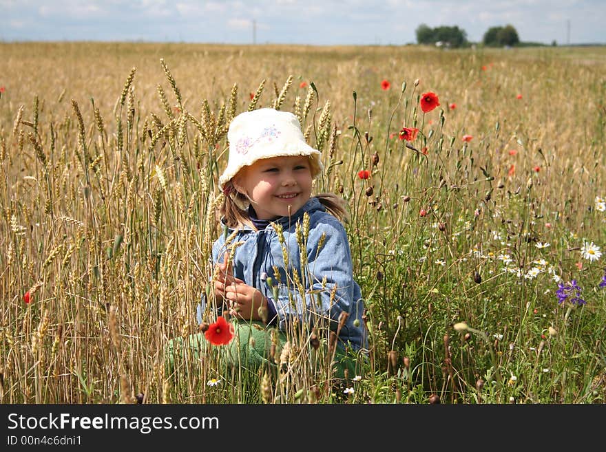 A girl holding red poppy flower,squatting in the wheat field