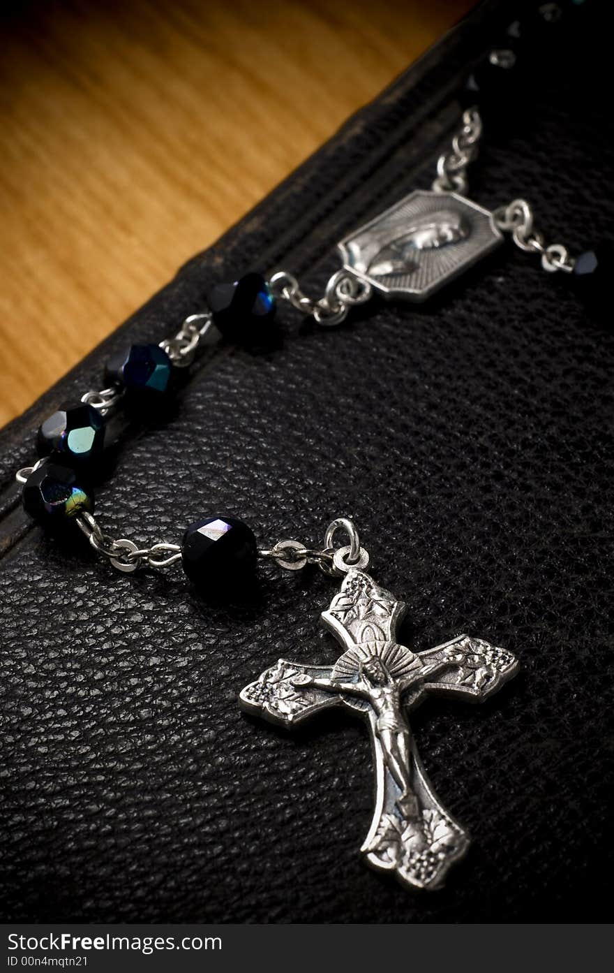 Rosary crucifix draped over antique leather bible. Rosary crucifix draped over antique leather bible