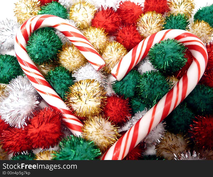 Pair of candy canes nestled in colorful shiny pompons. Pair of candy canes nestled in colorful shiny pompons