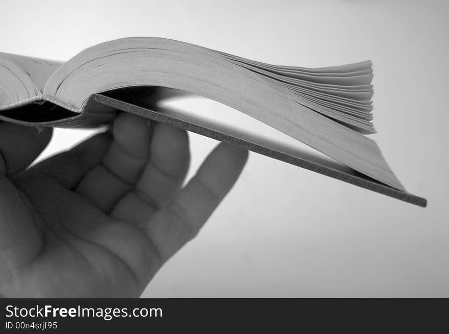 Black and white image of hand holding book. Black and white image of hand holding book