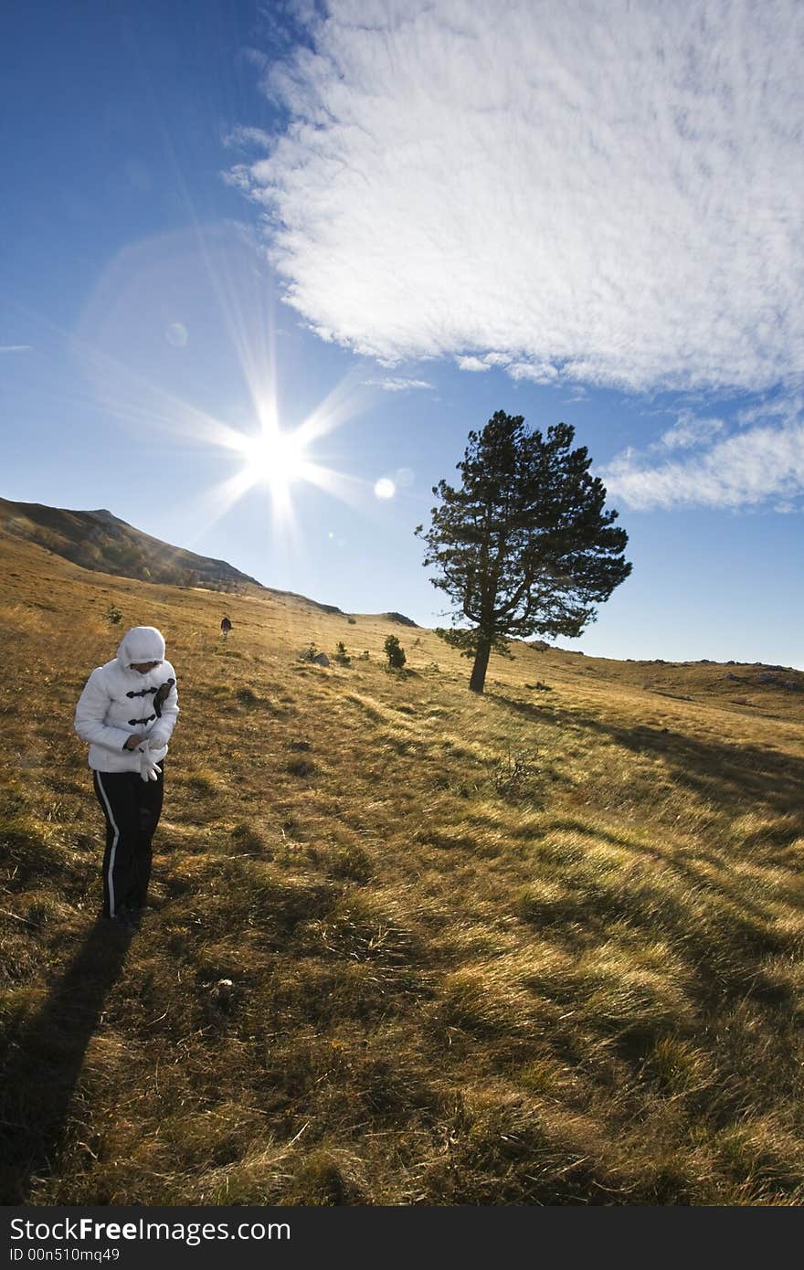 Couple hiking up the hills with the woman standing and preparing her gloves and her husband in the background walking away. Location: Nanos, Slovenija