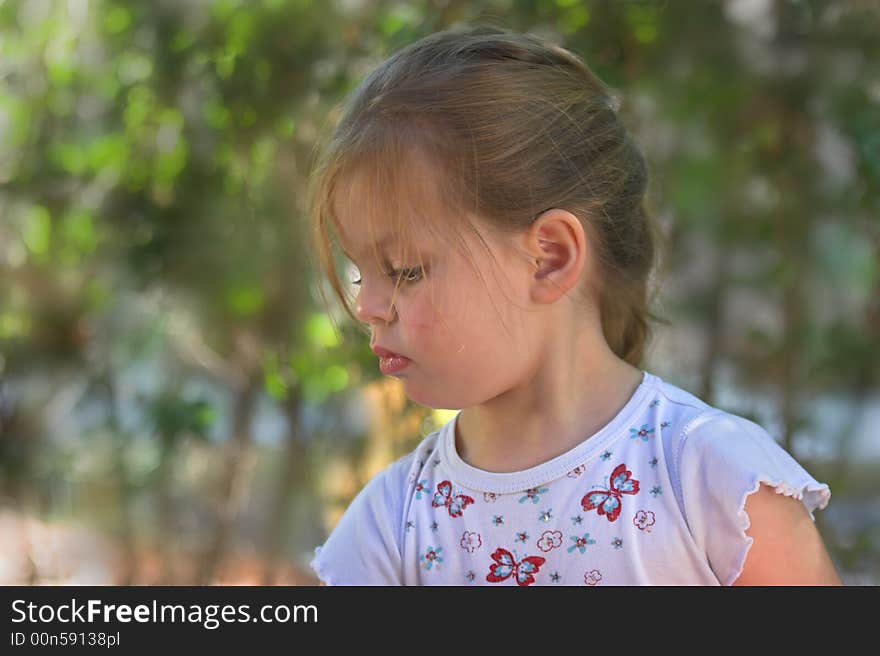 The small serious girl plays to a garden. The small serious girl plays to a garden